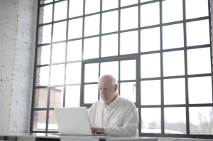 man in white shirt sitting in front of MacBook.