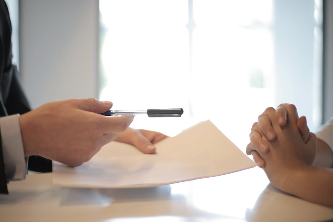 a person handing over a pen and paper.
