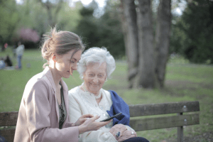 Da woman is explaining to senior how to use a smartphone.