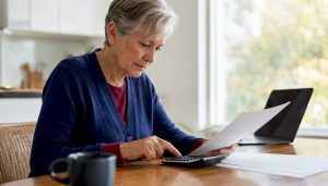 Senior calculating Medicare costs at home