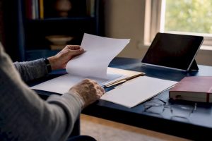 Hands organizing Medicare enrollment documents on desk