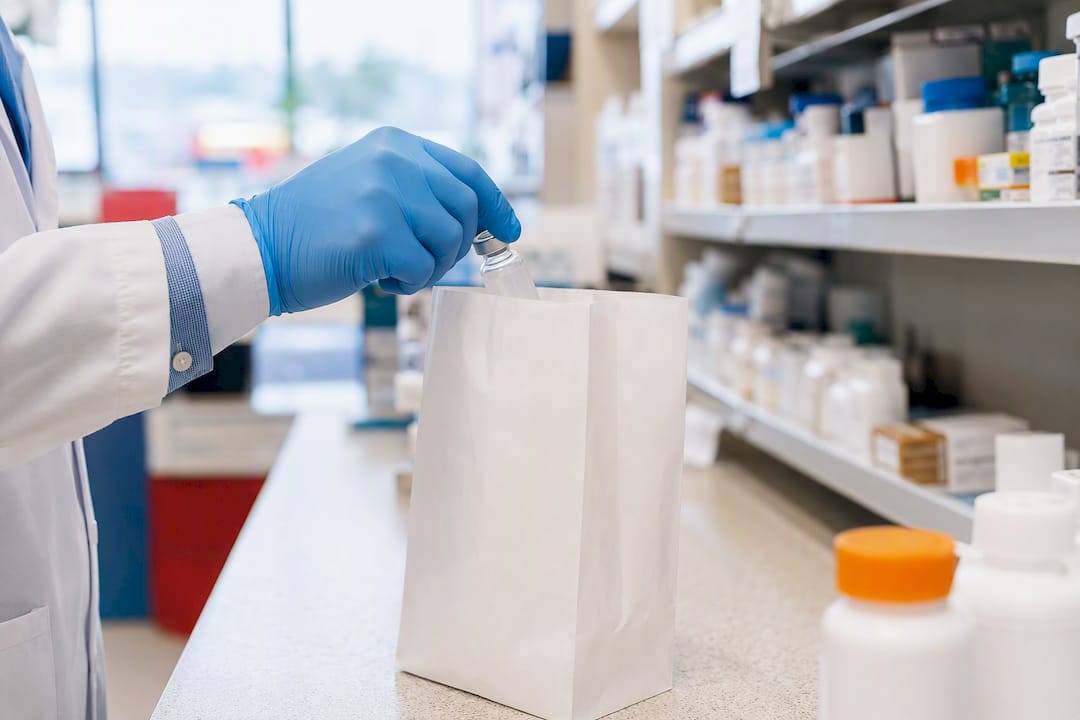 Pharmacist placing insulin vial into prescription bag