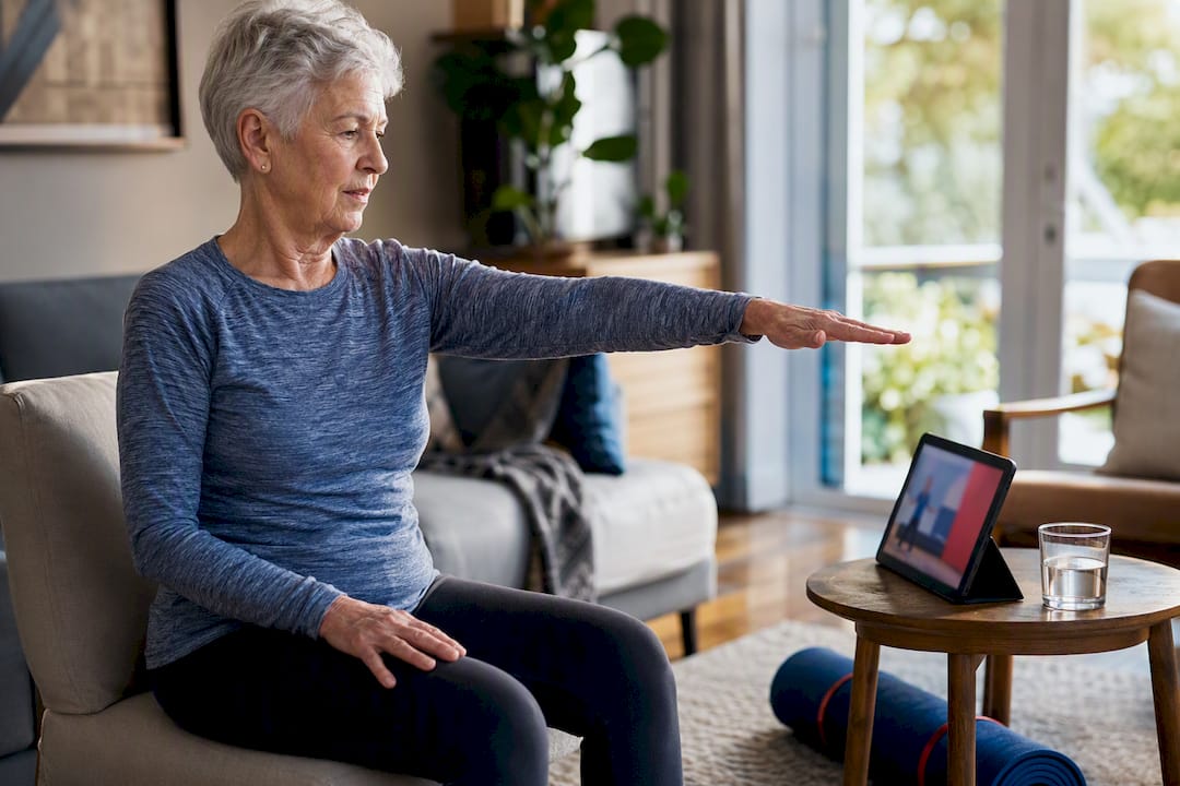Senior following an online fitness class at home