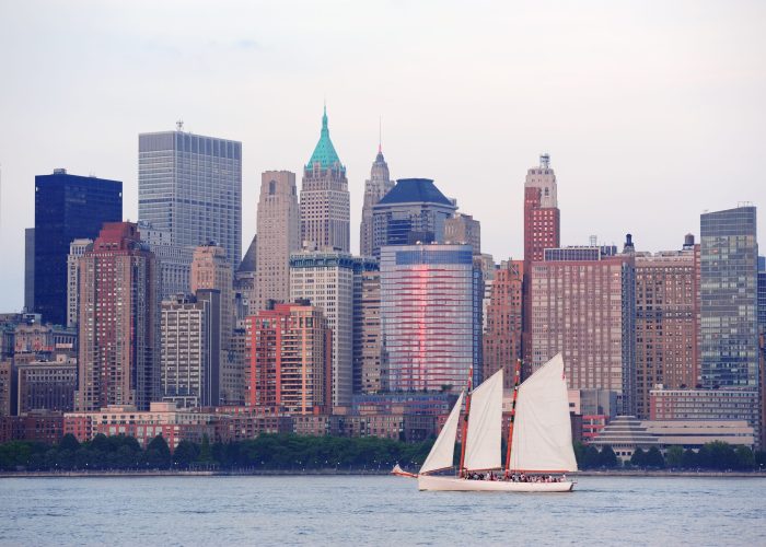 New York City Manhattan downtown skyline with boat at sunset over Hudson River panorama