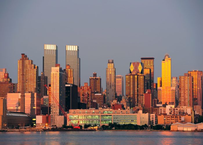 New York City Manhattan sunset panorama with historical skyscrapers over Hudson River with beautiful red color sunshine reflection viewed from New Jersey Weehawken waterfront.